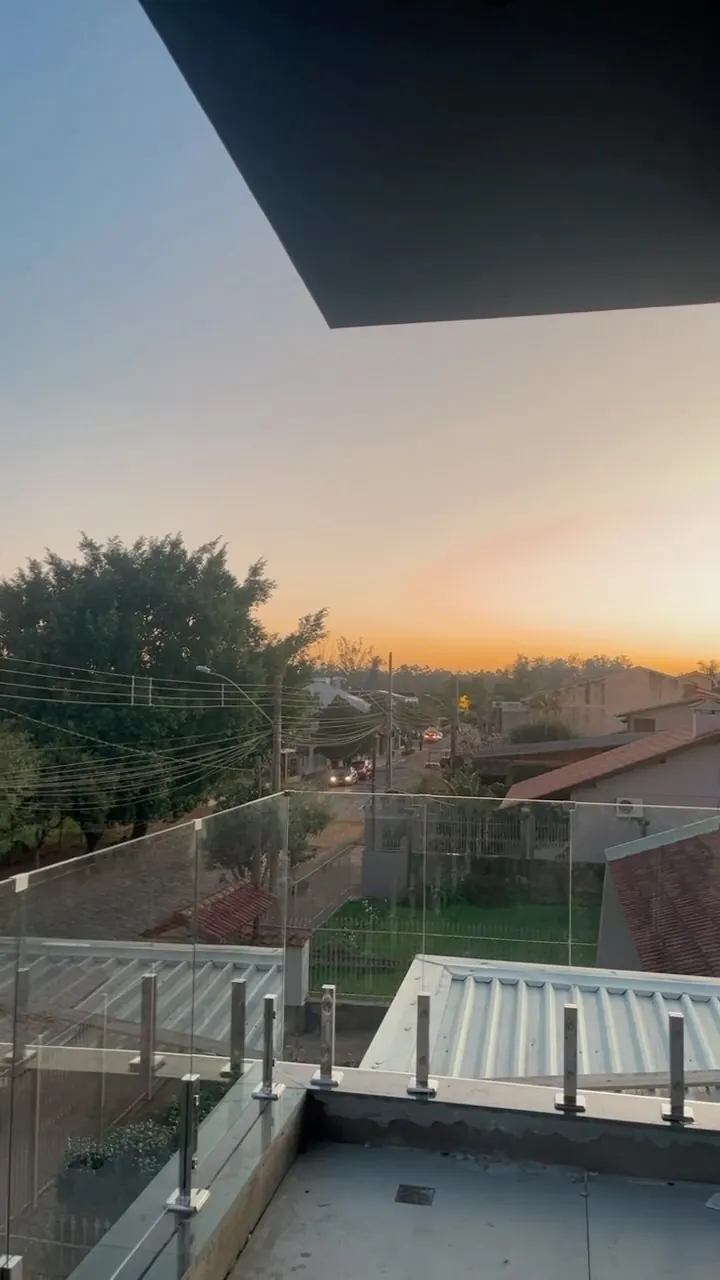Sacada com guarda-corpo de vidro ao pôr do sol