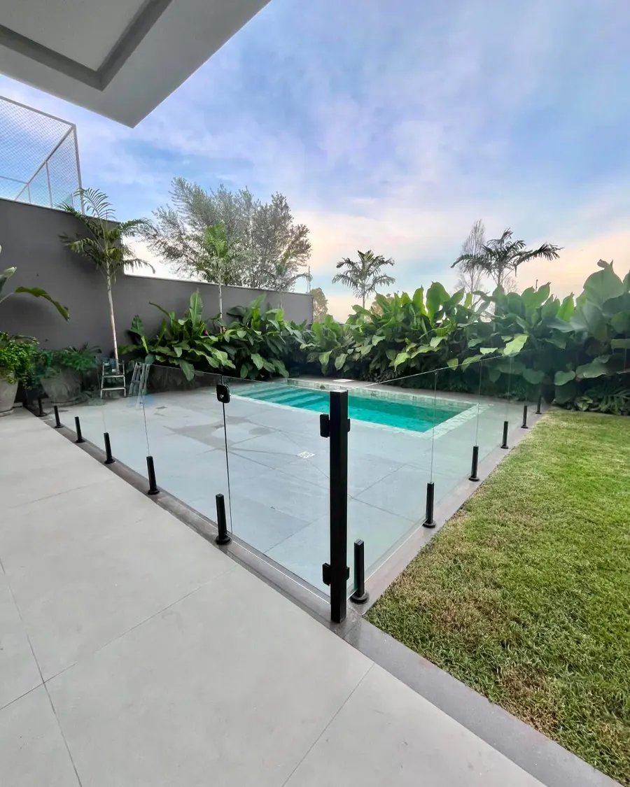 Guarda-corpo de vidro ao redor de piscina com torres de pinça pretas