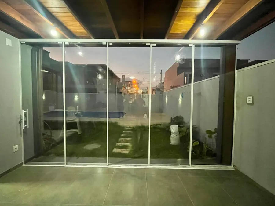 Portas de vidro sistema mão amiga com alumínio branco vistas à noite