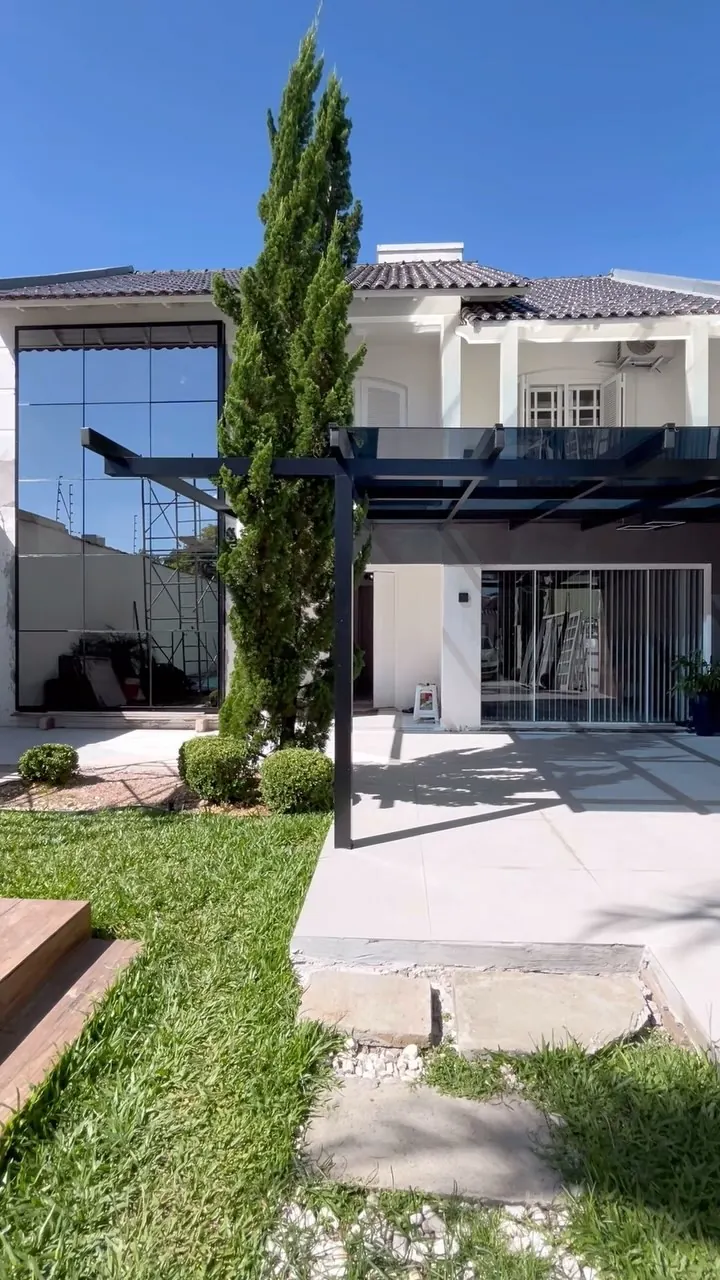 Casa com estrutura de telhado em alumínio preto e vidro