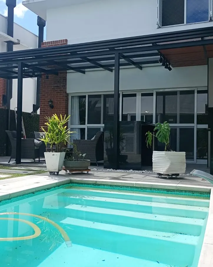 Pergolado em alumínio preto com ripado amadeirado e vidro fumê sobre área de piscina